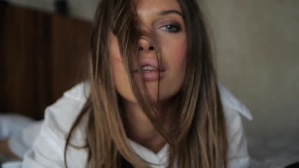 Sensual Brown-haired Woman Lying on the Bed and Looks at the Camera.