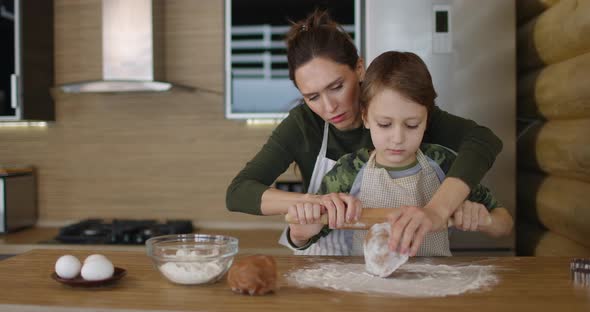 Mother and Little Son Making Handmade Cookies at Home Rolling Raw Dough Together at Kitchen