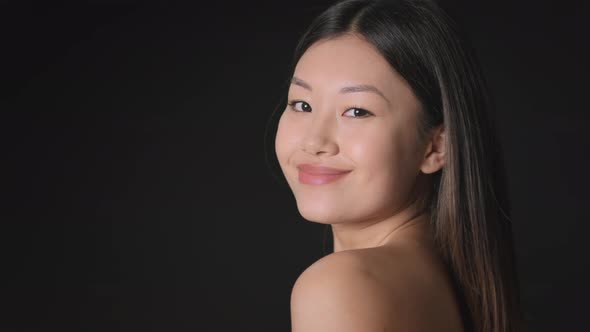 Young Korean Lady with Perfect Skin Posing Over Black Background Smiling to Camera with Bare