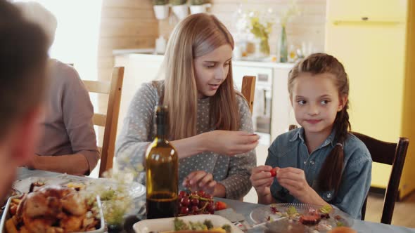 Two Little Sisters Eating Grape at Family Dinner