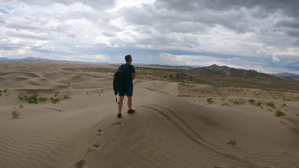 Following person walking on sand dunes through the Utah desert