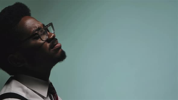 Stylish African American in Glasses and White Shirt Sings and Enjoys Music. Man on a Gray Background