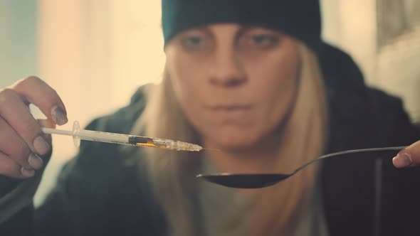 Woman with Syringe and Spoon Preparing Dose of Narcotics