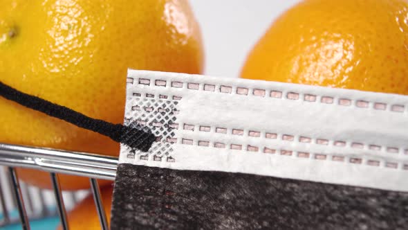 Ripe citrus in a supermarket cart with a wearing medical protective disposable mask 