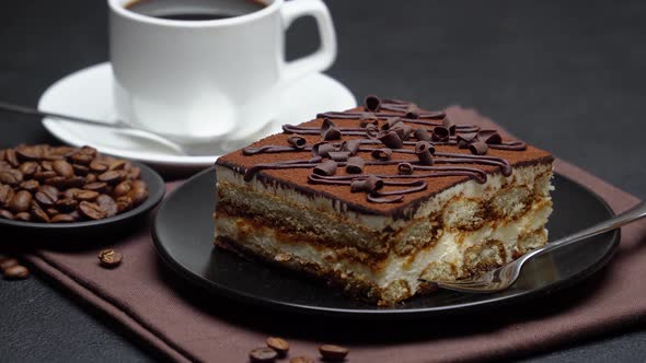 Portion of Traditional Italian Tiramisu dessert, cup of espresso coffee and coffee beans