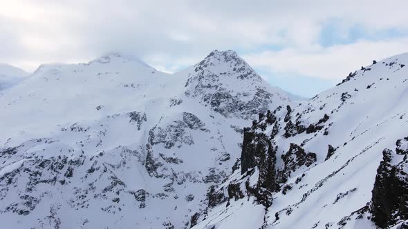 Rocky Mountains with Snowy Peaks Under Cloudy Sky in Winter