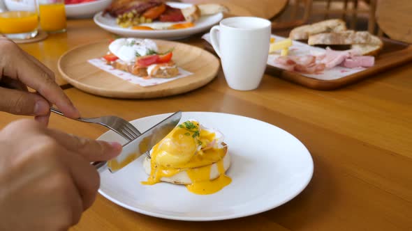 Unknown Man Eat Poached Egg Benedict Sandwich on Breakfast in Restaurant or Cafe