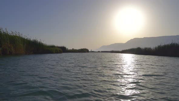 A River Surrounded By Reeds On A Flat Plain at Sunset