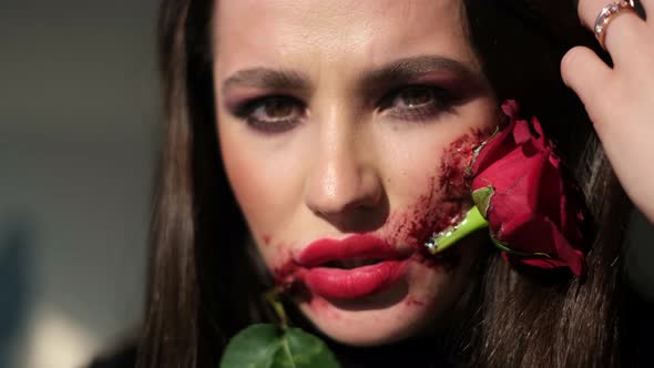 Glamorous Brunette Woman with Makeup for Halloween Rose Flower in Her Mouth