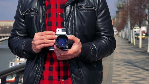 A Man Holds a Camera Against His Chest in a Street - Closeup