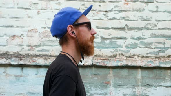 Portrait of young red bearded man in black t-shirt and snapback in rock style on urban background