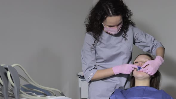 The orthodontist using dental impression tray on woman teeth