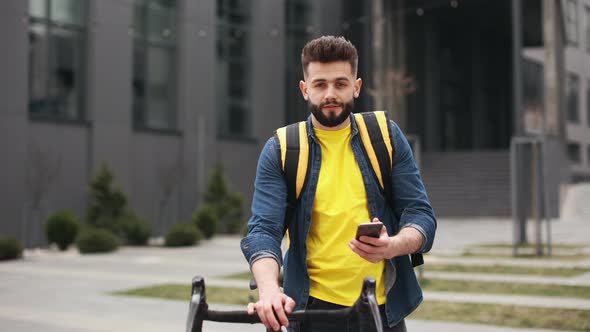 The Food Delivery Guy is Standing and Looking at the Camera