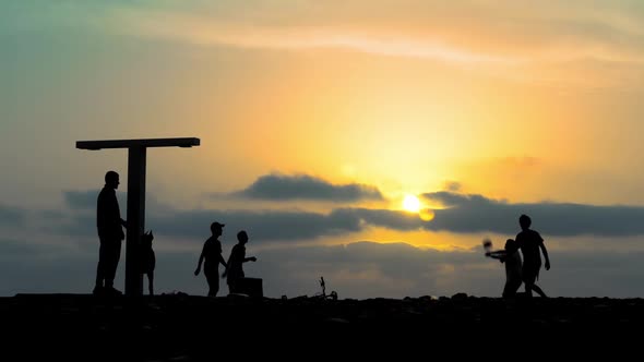 Silhouette of active people playing volleyball against sky on seashore at sunset