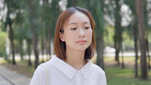 Cute short-haired Asian girl is walking in the park watching the sunset.