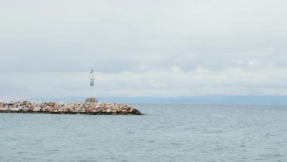 Alone Lighthouse on a Rocky Seashore and Calm Sea Water