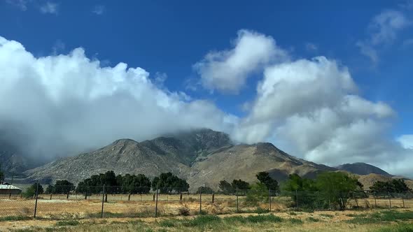 4k time-lapse of rural mountain landscape with blowing clouds swirling around the mountain through b