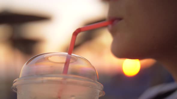 Woman enjoying iced drink outdoor at sunset