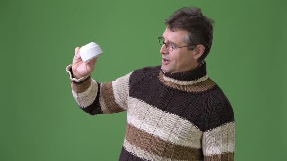 Mature Handsome Man Wearing Turtleneck Sweater Against Green Background