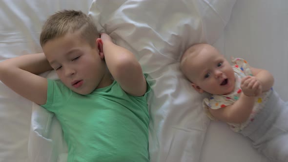 Brother with Junior Sister on Bed at Home