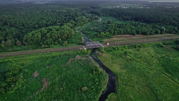 Railway Bridge Among Green Meadows Over a Small River in the Countryside