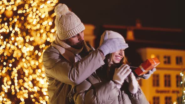 Man Giving Christmas Gift to Woman on City Street