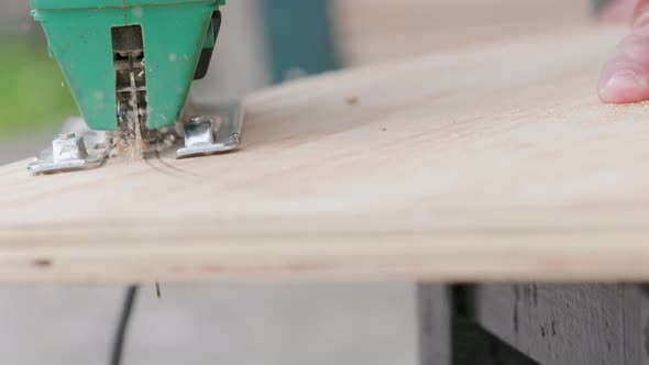 Sawdust Flies Off a Metal Blade As the Jigsaw Cuts Into a Sheet Plywood Workpiece