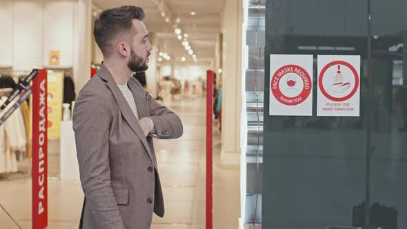 Man Putting On Face Mask Before Entering Clothing Store