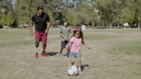 Front View of Disabled Dad Son and Daughter Kicking Ball Around