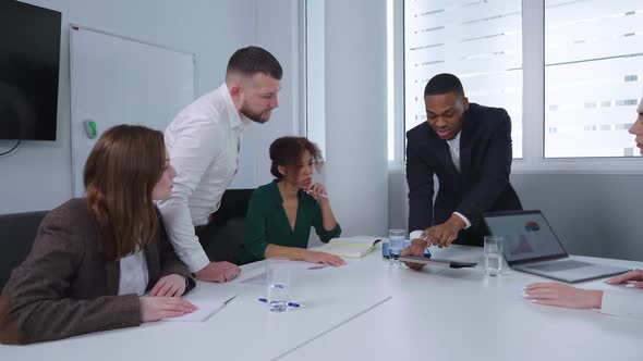 Black Businessman Showing Graphics to Team at Meeting