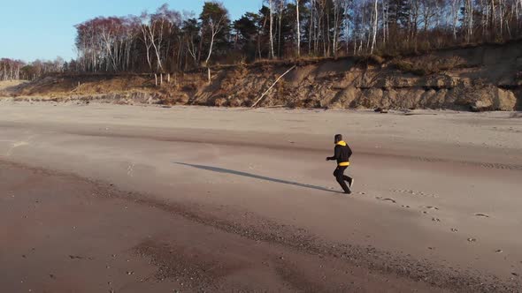 The man in black runs along the beach