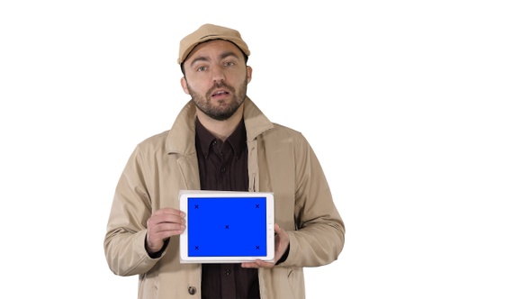 Man in trench walking and holding tablet with blue screen