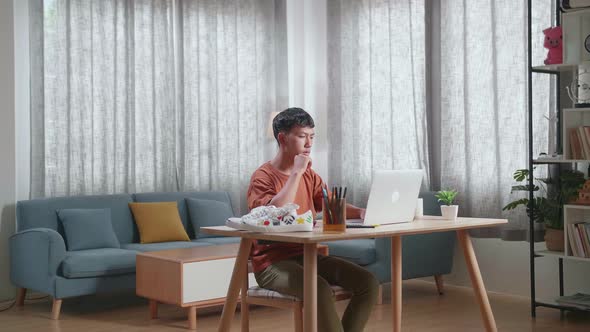 Asian Boy Footwear Designer Thinking Then Raising Index Finger While Working On A Laptop At Home