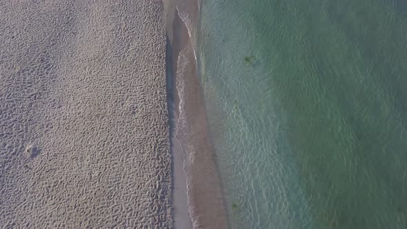 Aerial Drone View of a Beautiful Beach and Sea Water on Sunrise with Man Walking on the Beach