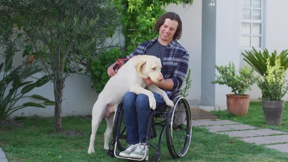 Smiling caucasian disabled man in wheelchair playing with pet dog in street