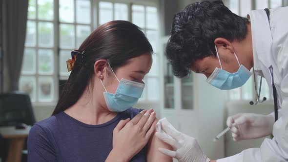 Doctor In Safety Gloves And Protective Mask Is Making A Vaccine Injection To A Female Patient alt