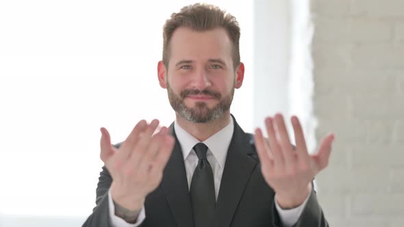 Middle Aged Businessman Pointing at the Camera and Inviting