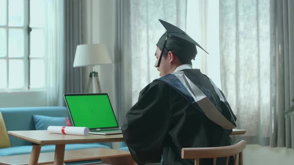 Asian Man Celebrating On Laptop Computer With Green Screen During An Online Video Call At Home alt
