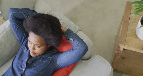 Happy african american woman laying on sofa with eyes closed