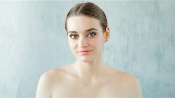 Beautiful Young Woman with Perfect Fresh Skin Looking at Camera