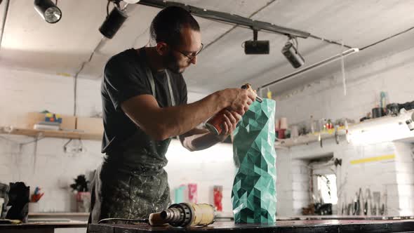 Male craftsman burns his product with a gas burner in the workshop