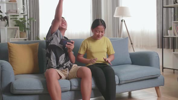 Children Playing Video Games On Mobile Phone At Home, Boy Celebrating Victory And Girl Disappointed
