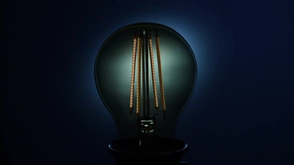 Electric Vintage Edison Light Bulb with a Spiral Flashing on a Blue Background