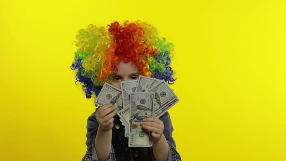 Little Child Girl Clown in Wig Making Silly Faces, Having Fun with Money Banknotes Dollar Cash