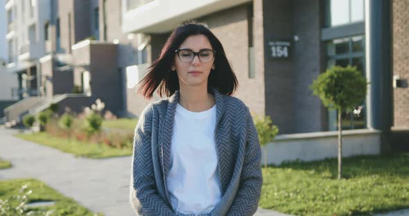 Caucasian Young Woman Looking Into Camera During Walking at Urban Street at Sunset