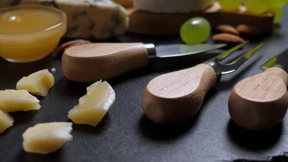 Sliced Cheese, Nuts, Grape, Honey and Knife on Shale Platter