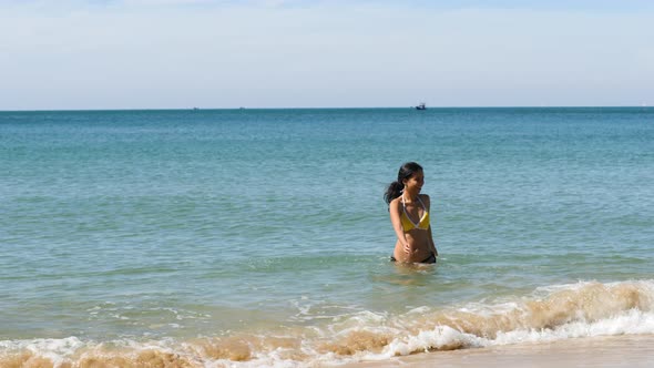 Beautiful and Carefree Young Pregnant Asian Woman Playfully Running in the Water