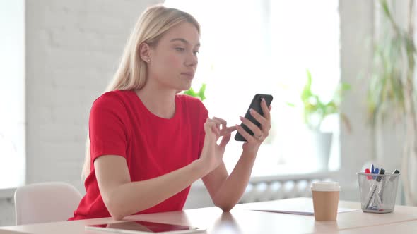 Successful Young Blonde Woman Celebrating on Smartphone