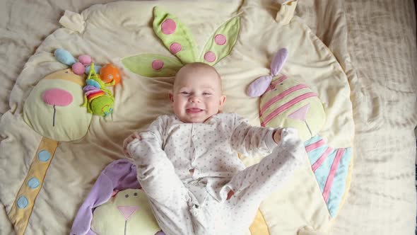 Adorable Baby Girl Learning to Crawl and Playing with Colorful Toys in White Sunny Bedroom