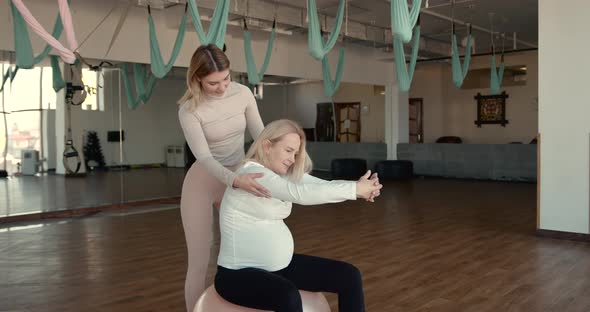 Pregnant Woman and Her Personal Trainer Doing Stretching Exercises